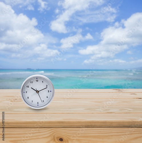 Clock on wood table top with sea background