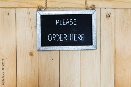 Order here sign hanging on wooden background