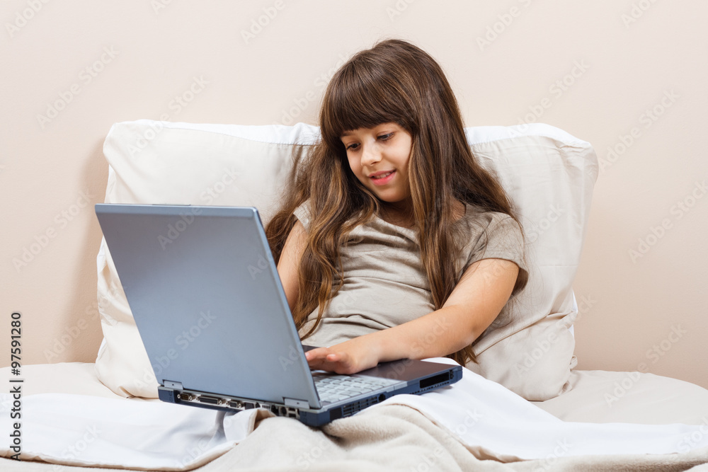 Little girl using laptop in bed Little girl using laptop in bed