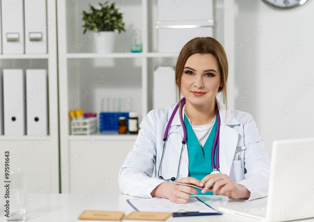 Beautiful friendly female doctor sitting at working table
