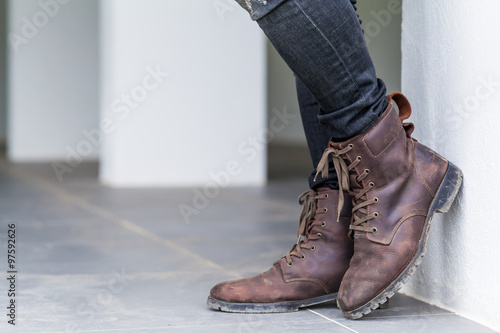 Young fashion man's legs in jeans and brown boots on the floor