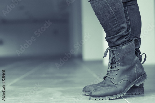 Young fashion man's legs in jeans and brown boots on the floor ,make it a green tone