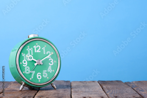 Retri clock on wooden table with blue background and space for text