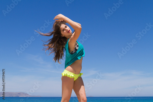 Brunette cheerful teenage in beachwear enjoys the summer.