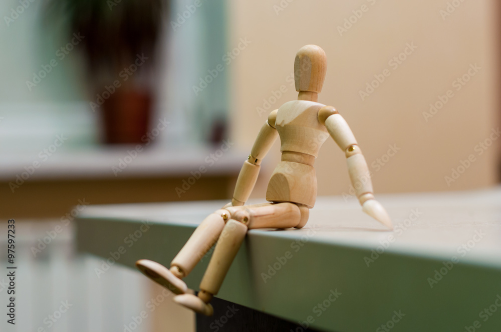 Wooden mannequin or man figurine sitting on white surface. Wooden mannequin or man figurine sitting on white surface.