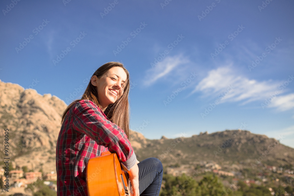 Smiling Woman sitting on a Rock with her Guitar in Madrid