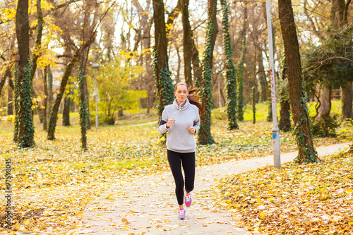 Sporty young woman running in the park and listening to music. Sport lifestyle. Motion blur.