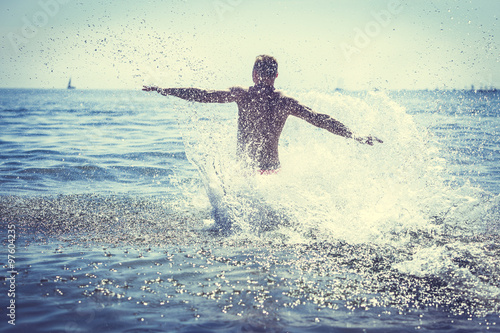 Man running splashing ocean sea water. Fun