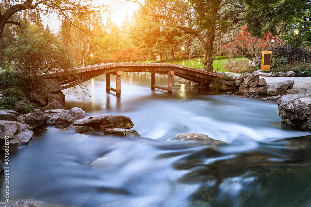 The stream and small Bridge in a Chinese garden in the sunset