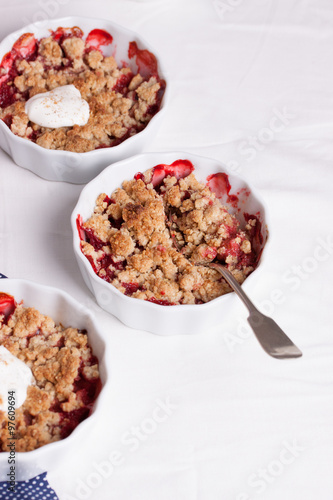 Crumble with oatmeal, wholemeal and strawberry in white bowls on a white table