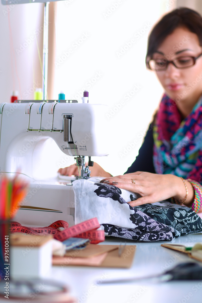 Young woman sewing while sitting at her working place