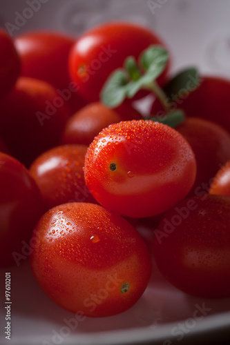 Cherry tomatoes in a white plate on a black background. closeup.
