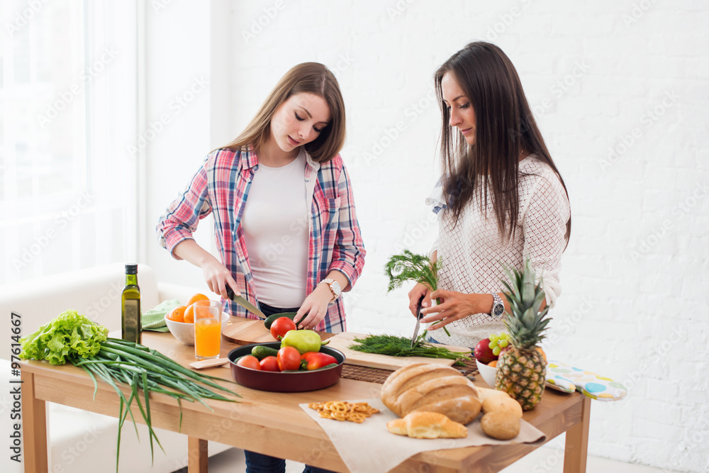 Foto Stock Two girls friends preparing dinner in a kitchen concept cooking,  culinary, healthy lifestyle | Adobe Stock