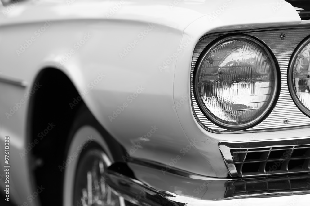 Close-up of left headlights of a white shiny classic vintage car