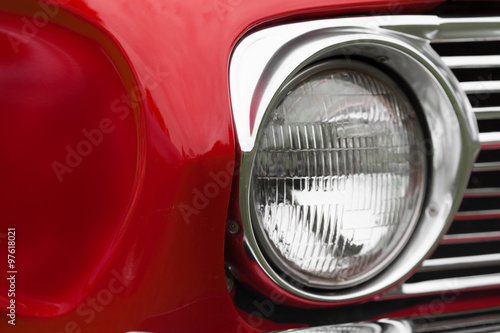 Close-up of left headlight of a red shiny classic vintage car © bruno135_406