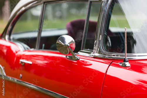 Close-up of wing mirror of a red shiny classic vintage car