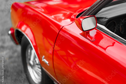 Close-up of wing mirror of a red shiny classic vintage car