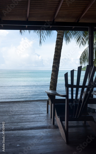 Adirondack chair at a tourist resort and sea viewed through open door of a tourist resort, Trinidad and Tobago