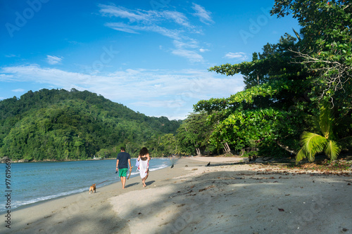 Rear view of couple with dog walking on sandy beach  Trinidad  Trinidad and Tobago