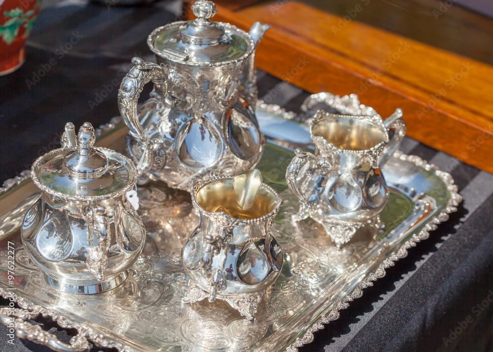 Luxurious silver cups and tea pots on tray for sale at flea market