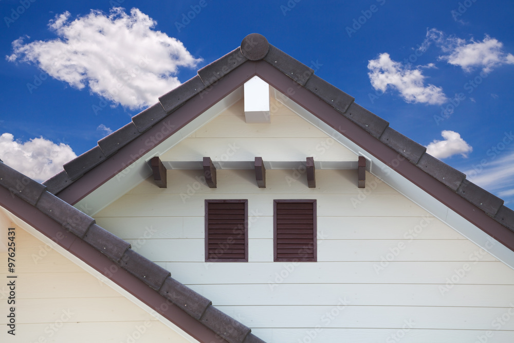 Detail of house exterior wall and blue sky with cloud.