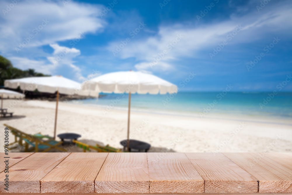 Wood table top on blurred blue sea and white sand beach backgrou