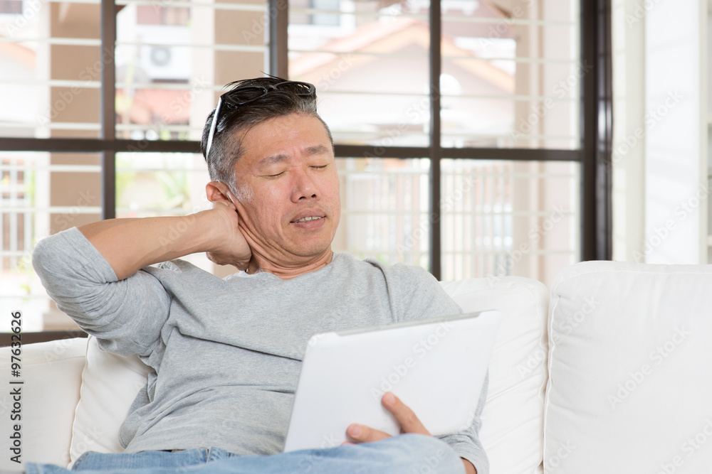 Mature Asian man neck pain while using tablet computer Mature Asian man neck pain while using tablet computer