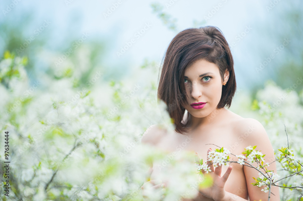 Closeup portrait of a young beautiful sexy brunette woman with white cherry flowers in bokeh background Closeup portrait of a young beautiful sexy brunette woman with white cherry flowers in bokeh background