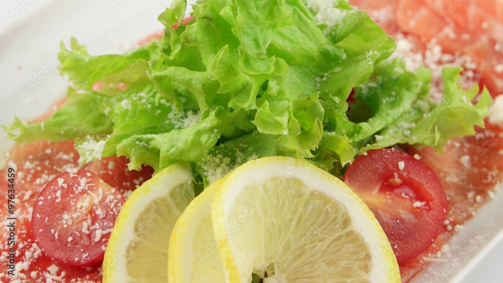 Smoked salmon carpaccio with lemon in long white plate (loop)