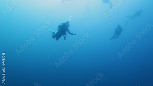 Group of Scuba Divers Swimming in Ocean Blue