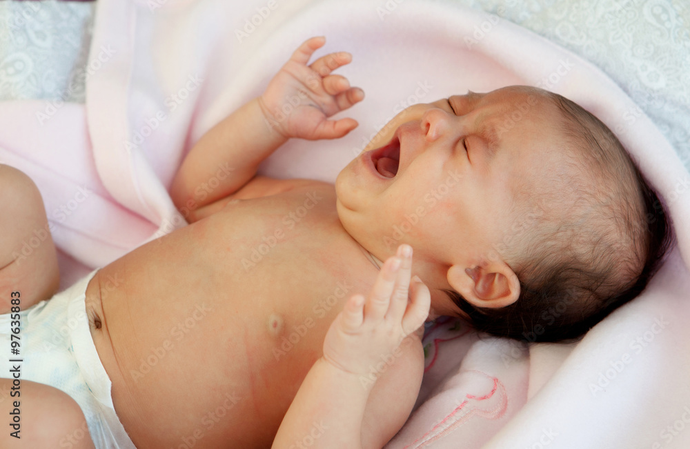Baby in diaper wrapped in a pink blanket crying Baby in diaper wrapped in a pink blanket crying