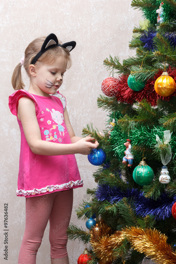 cat painted little girl decorates Christmas tree with toys cat painted little girl decorates Christmas tree with toys