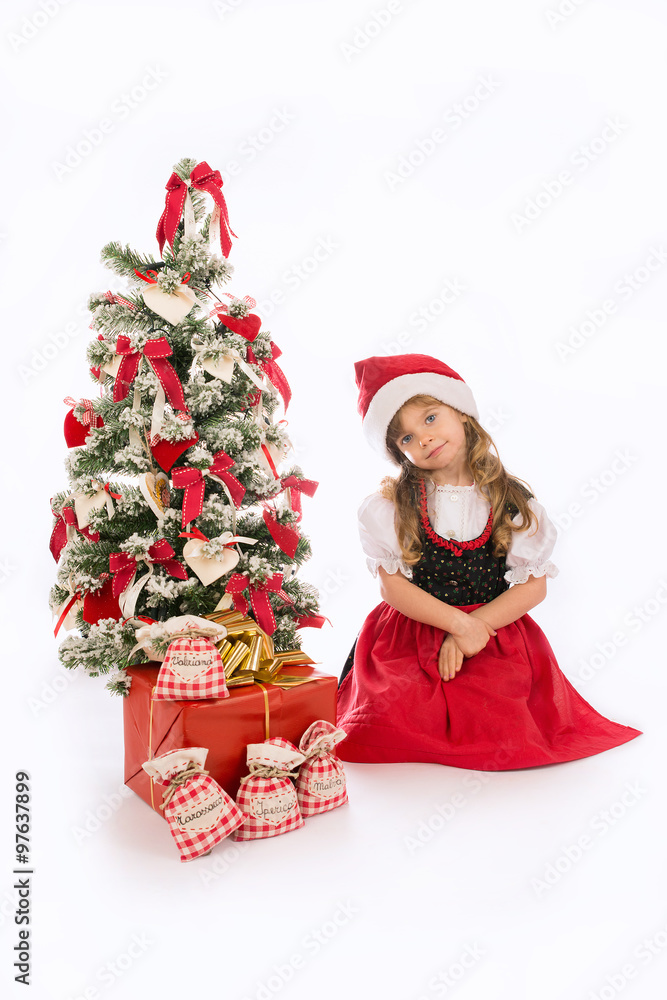 Bambina seduta con cappello e albero di Natale