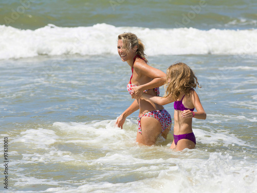 Happy blonde mother and daughter play among waves of sea © Belphnaque