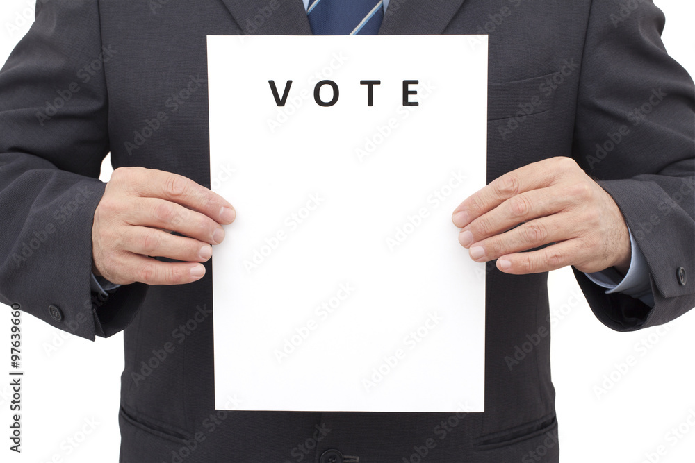 Man in suit, holding a white sheet with title VOTE in front of him. Man in suit, holding a white sheet with title VOTE in front of him.