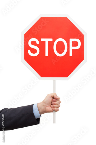 Man's hand in a blue shirt and jacket is holding a red sign STOP.
