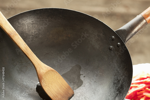 Wok cooking - small amount of sesame oil in wok pan, with bamboo ladle; close up; 