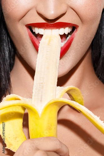 Sexy woman with red lips eating banana