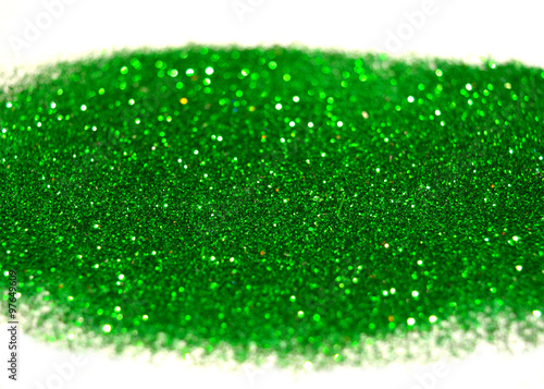 Blurry background of green glitter sparkles on white surface