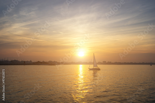 a boat sailing on the sea with the sunset as background - nature, transportation and lifestyle concept © Davide Angelini