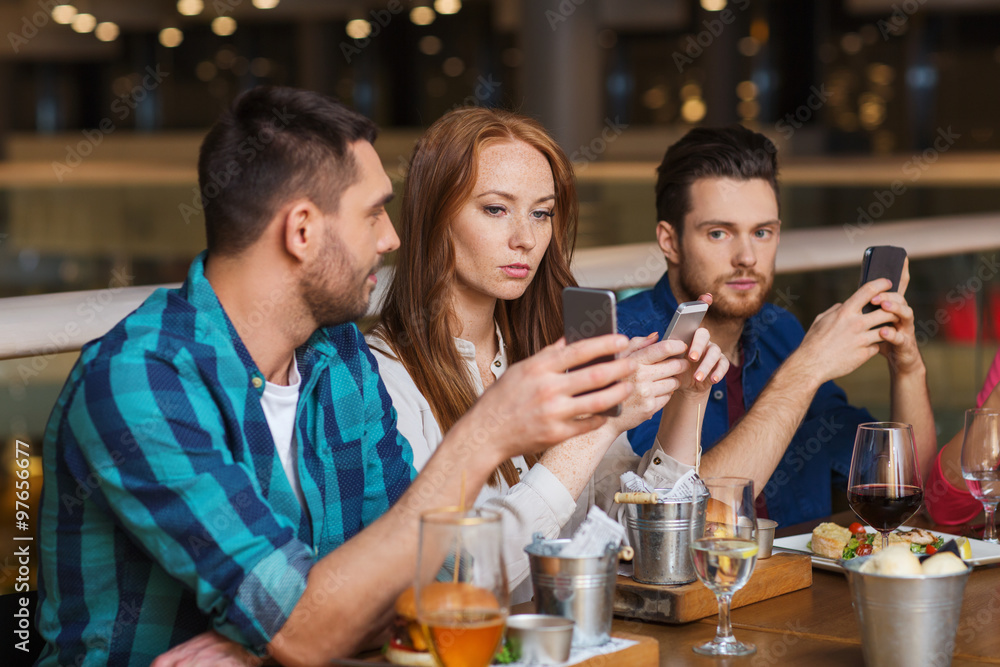 friends with smartphones dining at restaurant friends with smartphones dining at restaurant