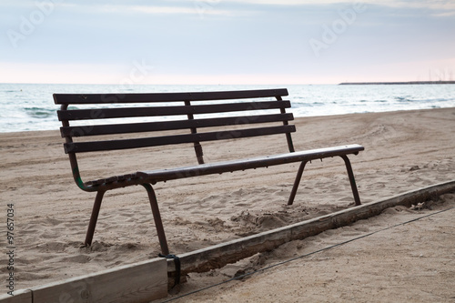 Old wooden bench stands on sandy beach