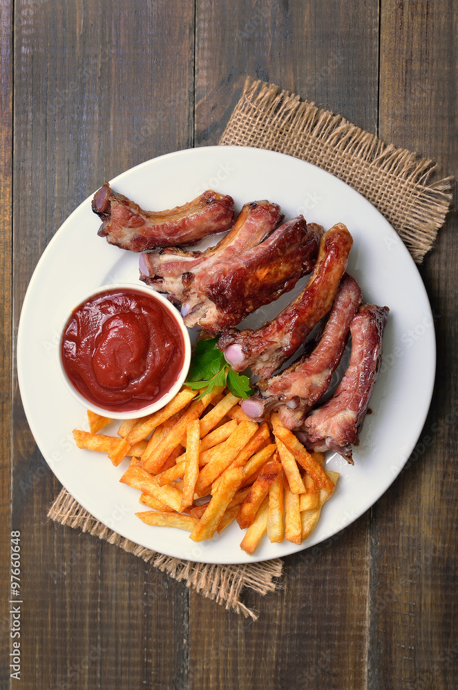 Fried pork ribs, potato fries and tomato sauce, top view Fried pork ribs, potato fries and tomato sauce, top view