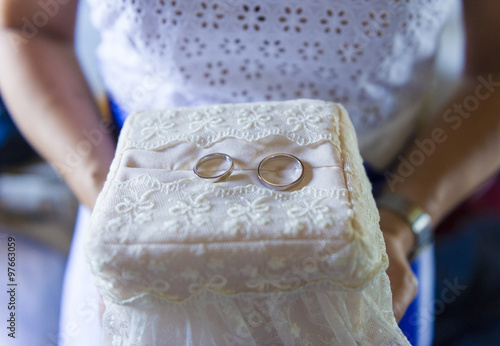Sposa regge nelle mani cuscino fedi matrimoniali con anelli photo