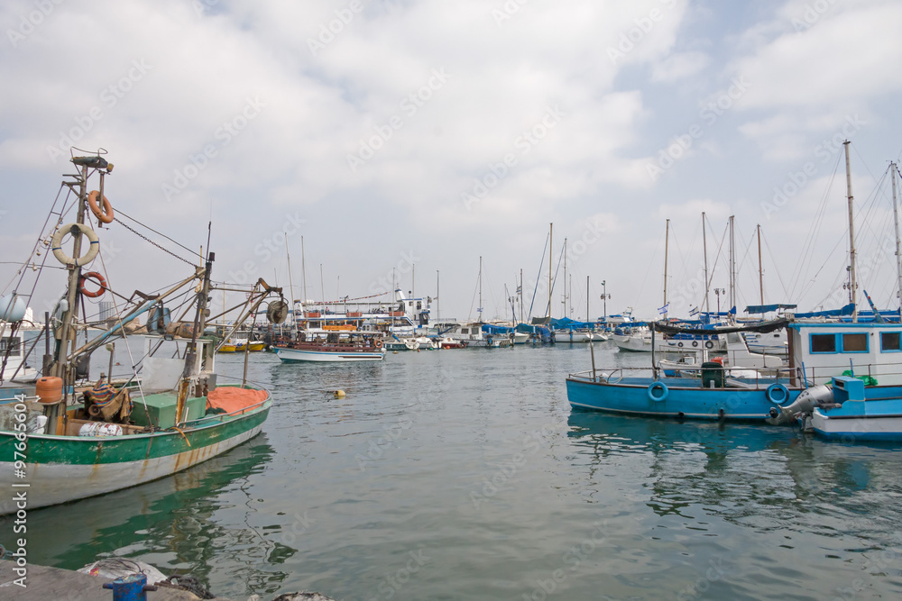 Fototapeta premium Wooden yachts moored in harbor against cloudy sky background. Acre, Israel. 