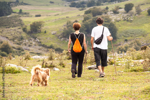 man and woman and dog on a summer walk in the mountains