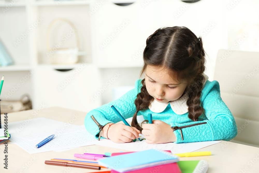 Cute little girl doing her homework, close-up, on home interior background Cute little girl doing her homework, close-up, on home interior background