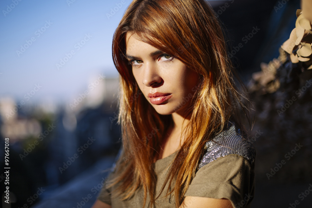 Beautiful redhead woman is enjoying the afternoon sun on the balcony.