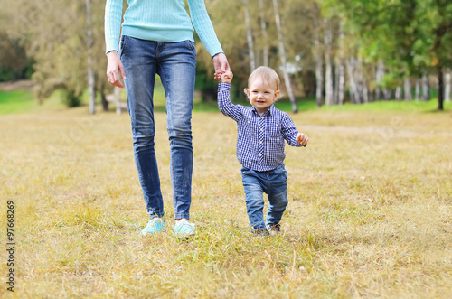 Happy mother and child walking together outdoors in park