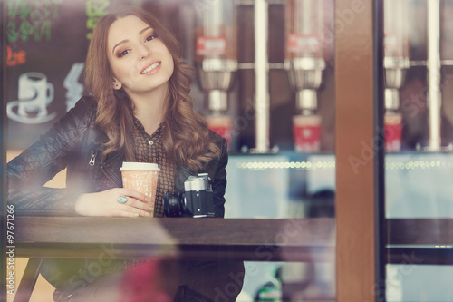 Young woman drinking coffee sitting indoor in urban cafe. Cafe city lifestyle. Casual portrait of teenager girl. Toned